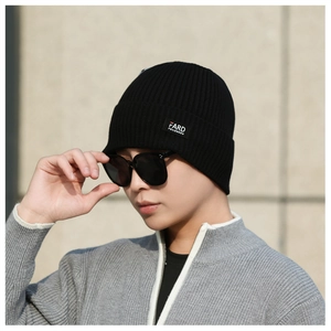 Close-up of black ribbed knit beanie featuring a square logo patch for a trendy winter look