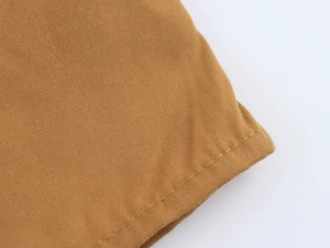 Close-up of brown cotton fabric showing detailed weave texture and double stitching seams