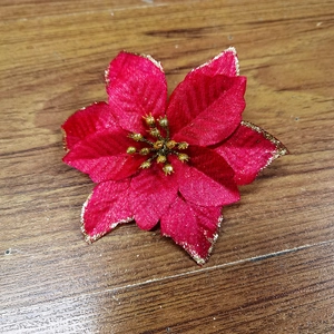 Close-up of red artificial Christmas flower with gold glitter edges and bead center