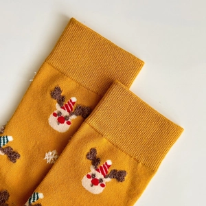 Detail of ginger yellow Christmas sock featuring an embroidered reindeer and snowflake