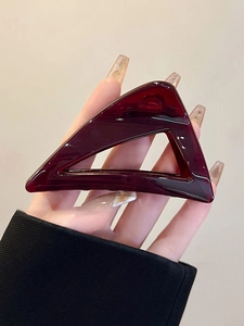 Detail of burgundy acrylic triangle hair claw clip with transparent amber texture