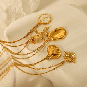 Layered gold stainless steel necklace with rose, moon, shell and sun charms on white stone