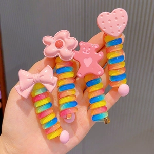 Close-up of four colorful rainbow spiral hair ties with cute pink cartoon charms