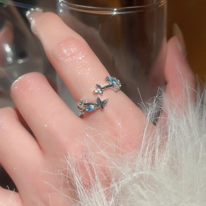 Detail of silver adjustable flower ring with blue zircon stones on a female finger