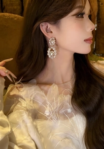 Close-up of elegant double layered pearl and rhinestone drop earrings on a model