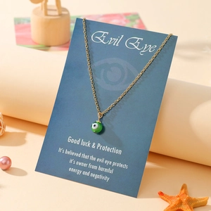 Golden evil eye necklace on navy blue gift card with seashell and starfish background