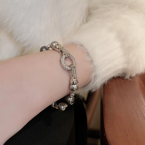 Detail eines grauen Perlenarmbands mit glitzerndem Kristallverschluss am Handgelenk