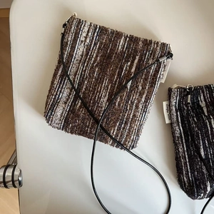 Close-up of retro crossbody phone bag featuring brown tweed texture and metal zipper