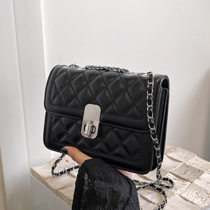 Detail of black quilted chain crossbody bag featuring silver hardware and twist lock