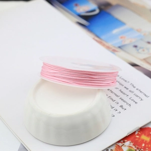 Pink braided cord for handmade jewelry making on a spool with a minimalist background