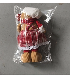 Detail of gingerbread man plush doll with red plaid apron and chef hat in packaging