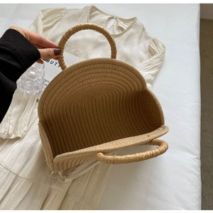 Detail of round handles on a khaki woven straw beach bag with a stylish half-moon shape