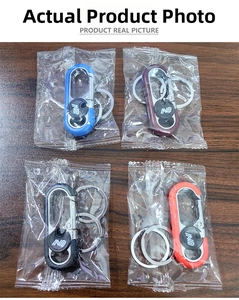 Detail of four colorful metal keychains with dual rings and embossed IND logo on wood