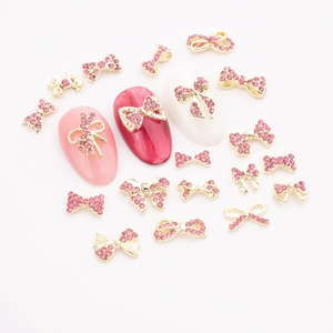 Detail of rose pink crystal bow nail charms on manicured tips with golden alloy base