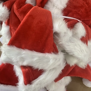 Detail view of stacked thick red plush Christmas hats with white fur trim for party decor