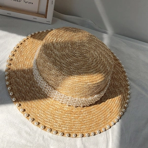 Detailed view of straw boater hat with elegant white pearl trim and flat top design