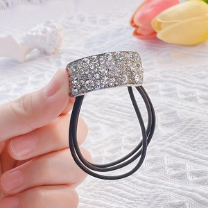 Dettaglio dell'elastico per capelli nero con placca d'argento incastonata di strass