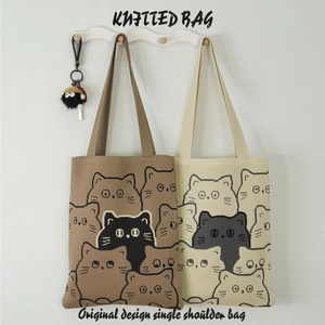 Close-up of knitted tote bags with cartoon cat patterns on a wooden hanger