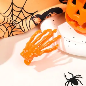 Detail of a bright orange skeleton hand hair clip on a festive Halloween spider web background