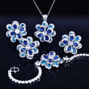 Exquisite floral jewelry set with blue zircon stones on a reflective dark surface