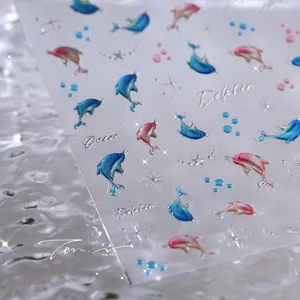 Macro shot of 5D embossed dolphin nail stickers with gradient blue and pink oceanic 3D patterns