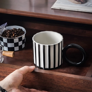 Artistic ceramic coffee mug with black and white vertical stripes and large round handle
