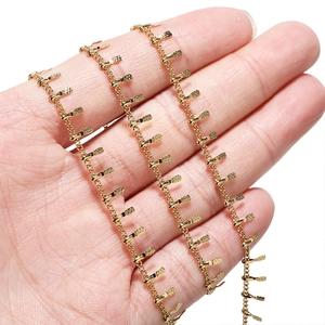 Golden fringe decorative chain with rectangular pendants shown in hand for scale
