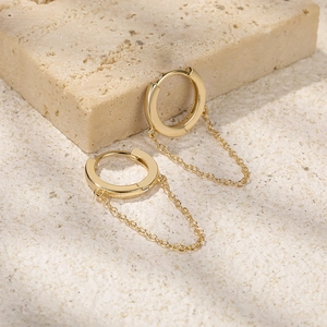 Macro shot of gold S925 sterling silver hoop earrings with dangling fine curb chains
