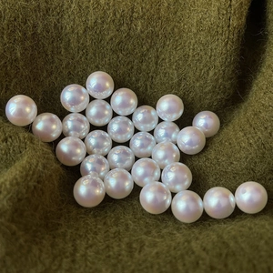 Macro detail of high-luster white and pink pearls on olive green knit fabric background