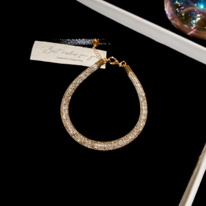 Macro shot of gold-plated bracelet with sparkling zircon stones on black velvet background