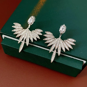Close-up of silver feather pendant earrings with leaf design and sparkling zircons
