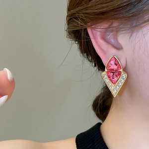 Close-up of vintage geometric diamond earrings with pink stones and gold-tone base