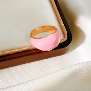 Chic pink enamel dome ring with gold finish on elegant white silk background