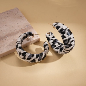 Zebra print leather wrapped C-shape hoop earrings with gold metal studs on warm background