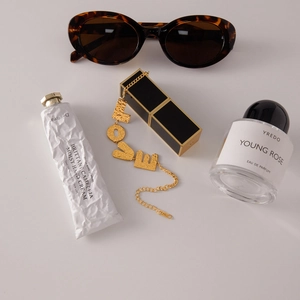 Detail shot of golden LOVE letter bracelet with hammered texture next to fashion accessories