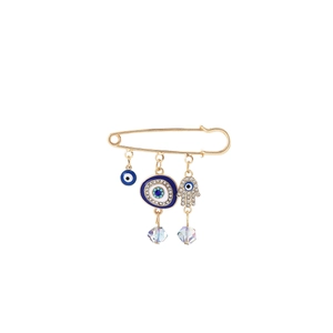 Detail of gold hamsa pin featuring blue evil eye charms and sparkling crystal tassels