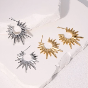 Moderne geometrische Ohrringe in Gold und Silber auf strukturiertem weißem Stein