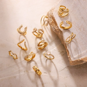 Macro shot of 12-piece gold titanium steel ring set with zircon on marble surface