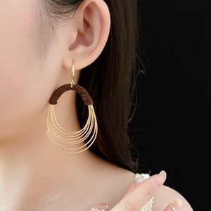 Detail view of multi-layered gold hoop earrings with brown woven cord on model