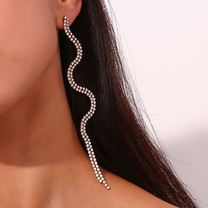 Detail of long wavy silver earrings with sparkling crystals worn on the ear