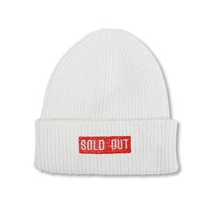 Gros plan d'un bonnet en maille blanc avec écusson rouge et broderie SOLD OUT