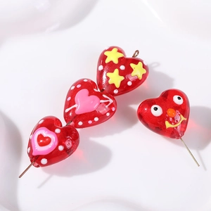 Macro detail of red heart-shaped glass bead with star and smile patterns for DIY jewelry