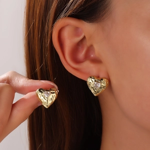 Detail of gold heart stud earring with textured metal surface and sparkling zircon stone