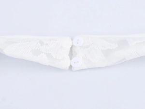 Detail of white mesh lace dress showing delicate embroidery and two round back buttons