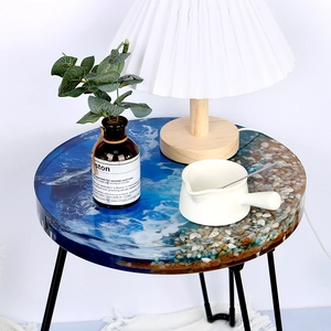 Detail of round ocean river table with resin waves, real shells and metal legs