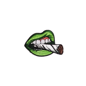 Vibrant green embroidered lip patch biting a rolled cigarette with black stitching