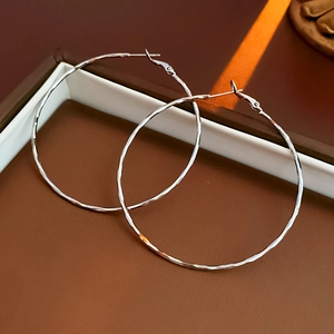 Detail of silver hoop earrings with a hammered texture in a gift box with warm lighting