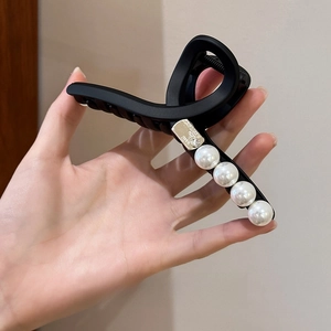 Détail macro d'une pince à cheveux noire mate de 13cm avec perles et accent doré