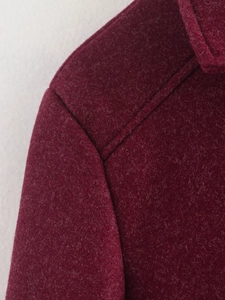 Nahaufnahme der weinroten Tweed-Jacke mit Schulternähten und strukturierter Wolloptik