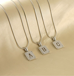 Macro view of silver stainless steel alphabet pendant with sandblasted finish and snake chain